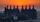 An expansive industrial refinery complex is silhouetted against a vivid orange sunset.