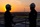 Two employees wearing hard hats and safety goggles with sunset in the background.