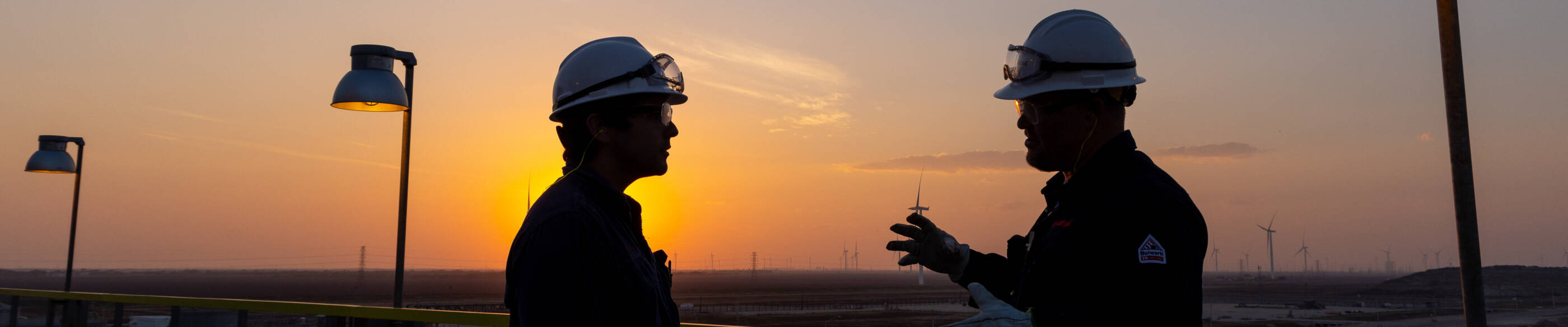 Two employees wearing hard hats and safety goggles